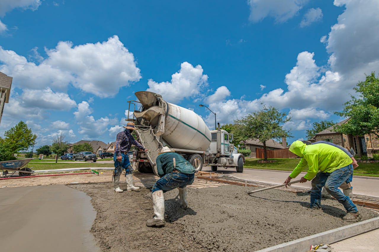 Construction workers laying concrete for a driveway in Fort Worth, Texas, under a bright blue sky.